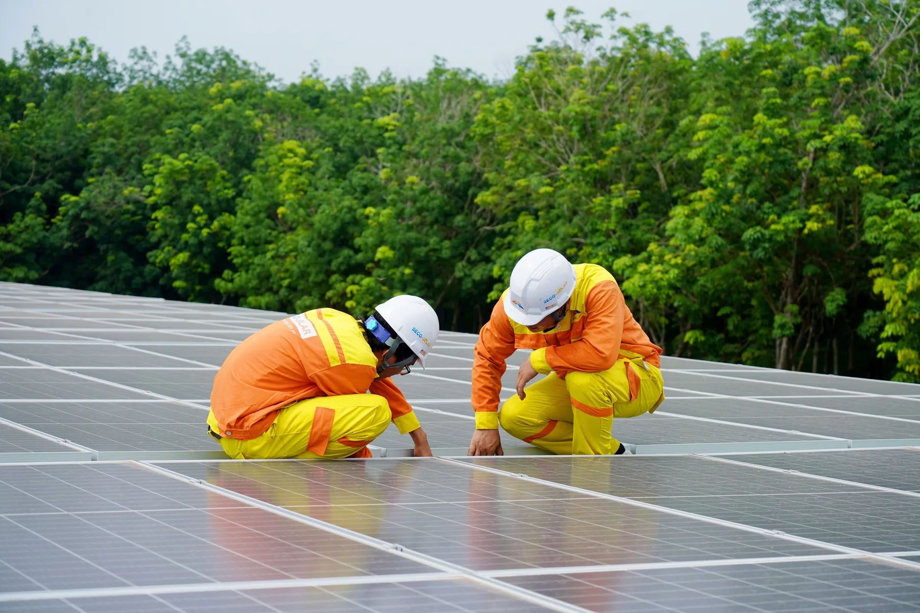 Two installers fitting a solar panel to a residential roof