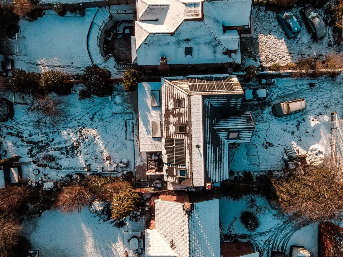 Snow-covered roof with solar panels clear of snow in winter sunlight